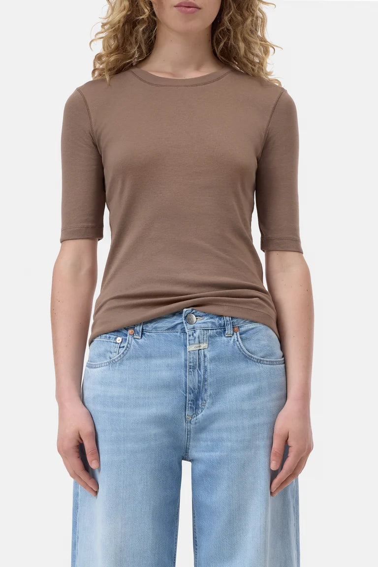 Person wearing a brown short-sleeve shirt and blue jeans on a white background