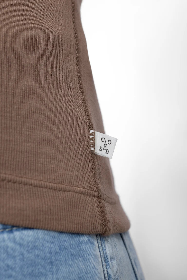 Close-up of a brown garment with a label on a white background