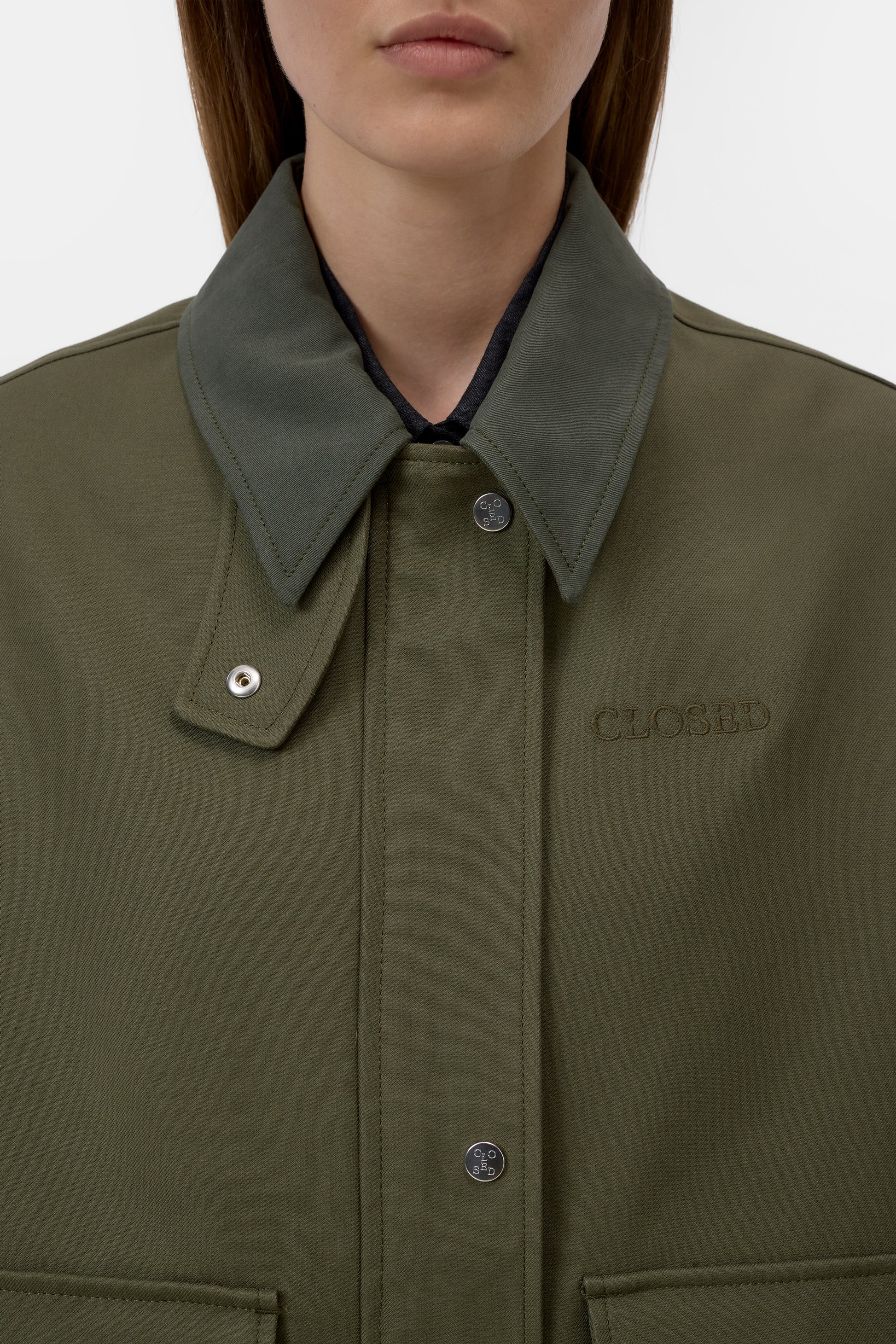 Close-up of a green jacket with a collar and 'Closse' branding on a white background