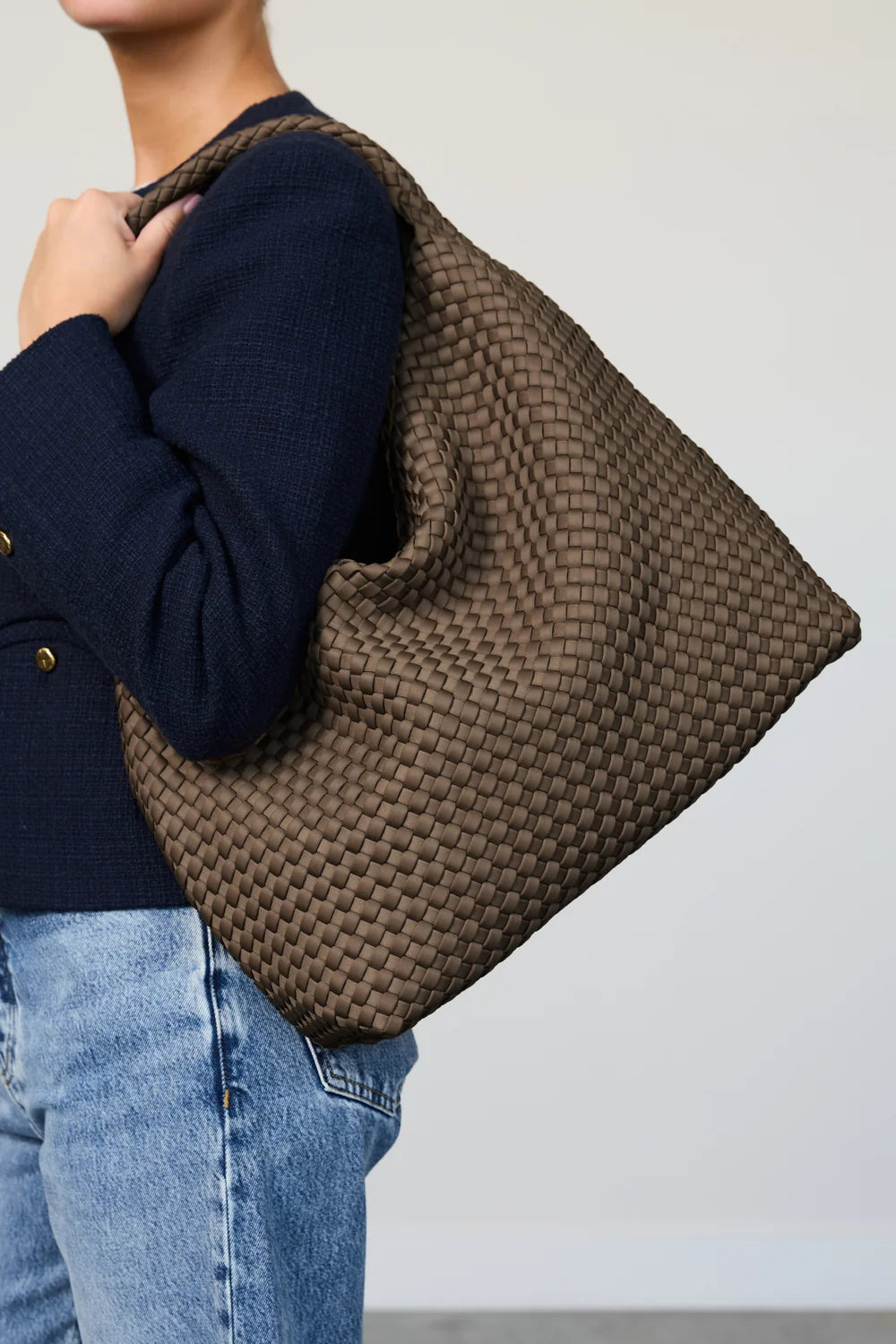 Person holding a woven brown bag against a plain background