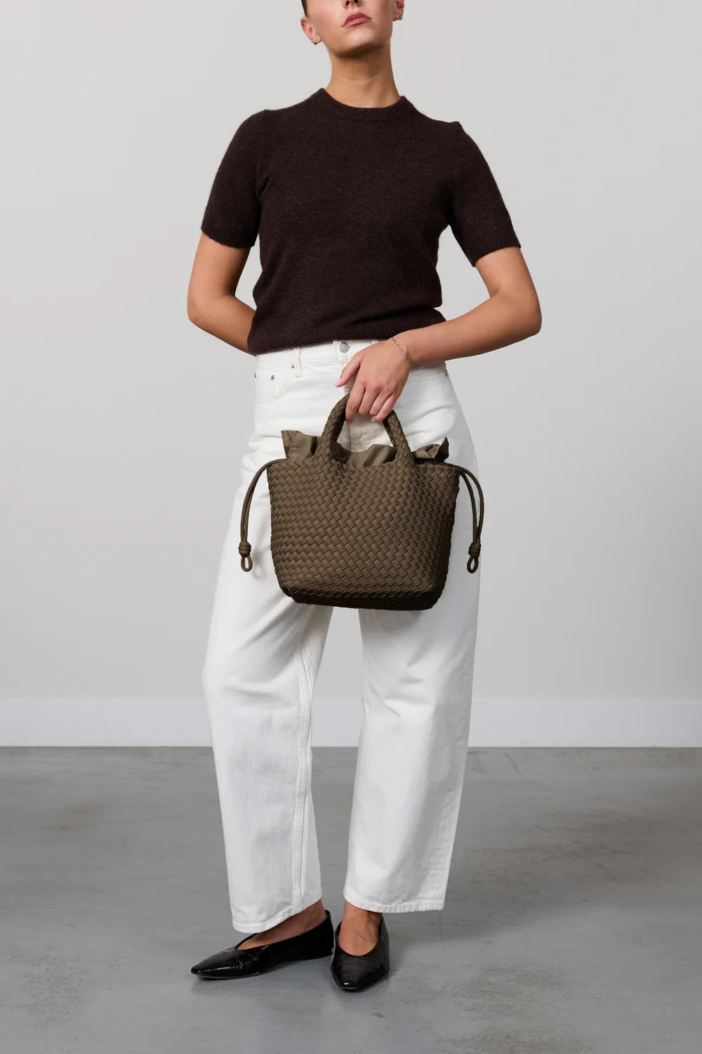 Person holding a woven handbag against a plain background