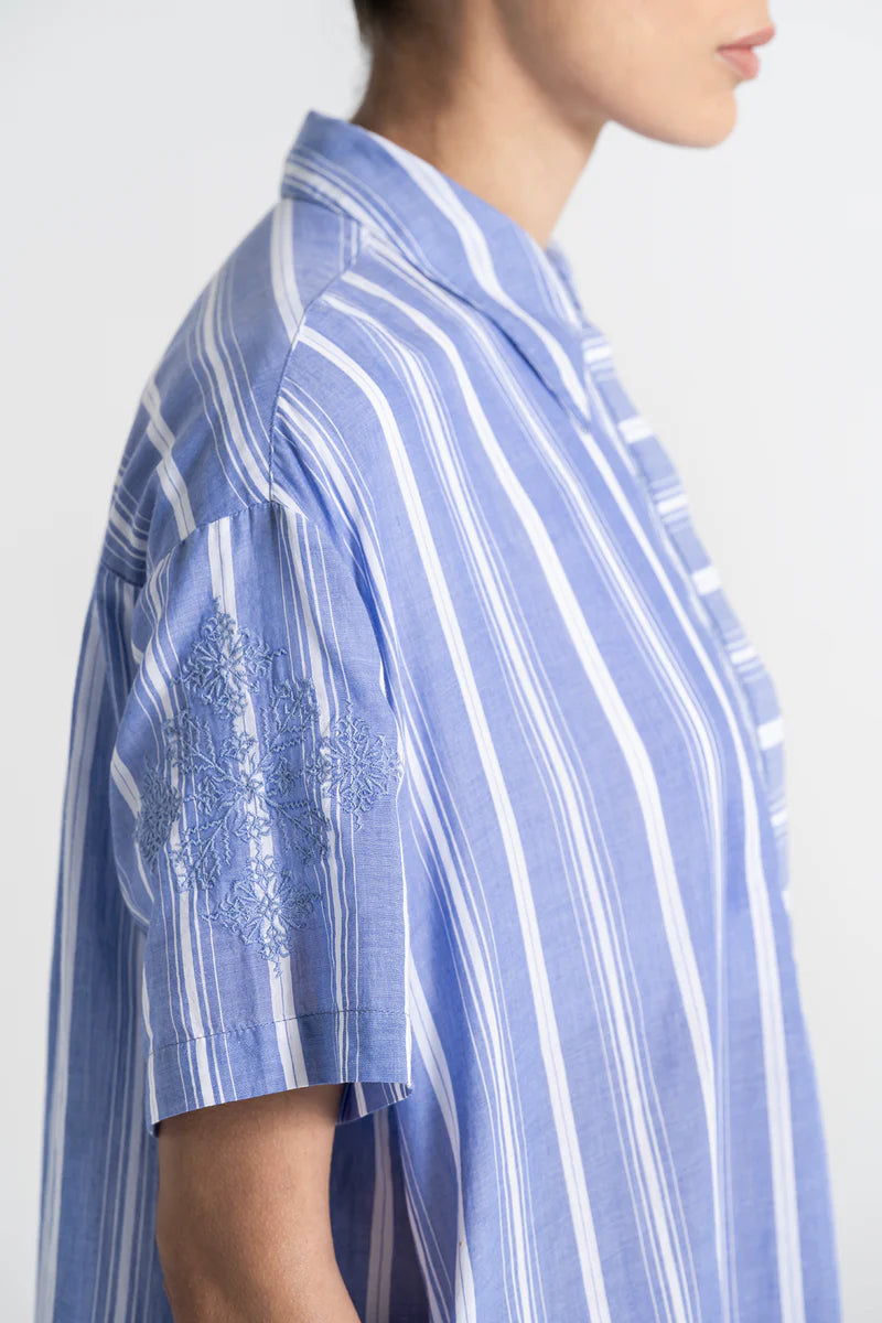 Blue and white striped shirt worn by a person on a plain background