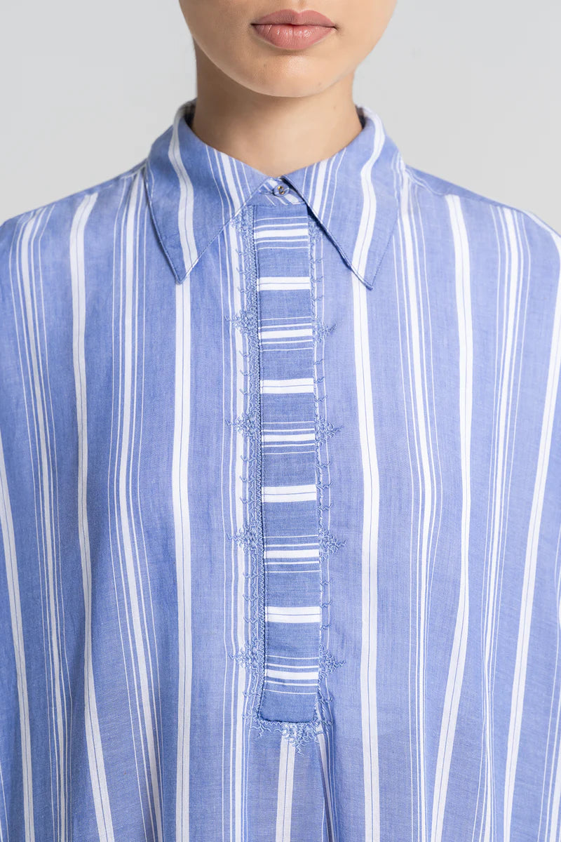 Close-up of a person wearing a blue and white striped shirt against a gray background