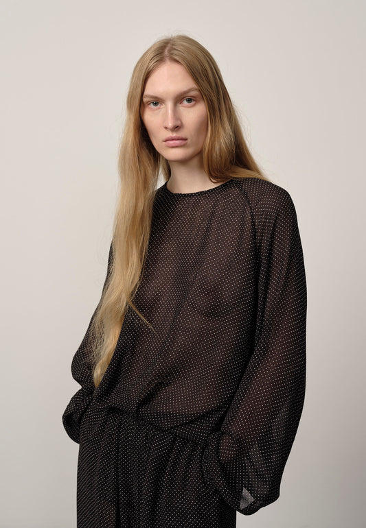 Woman wearing a black mesh outfit against a plain background
