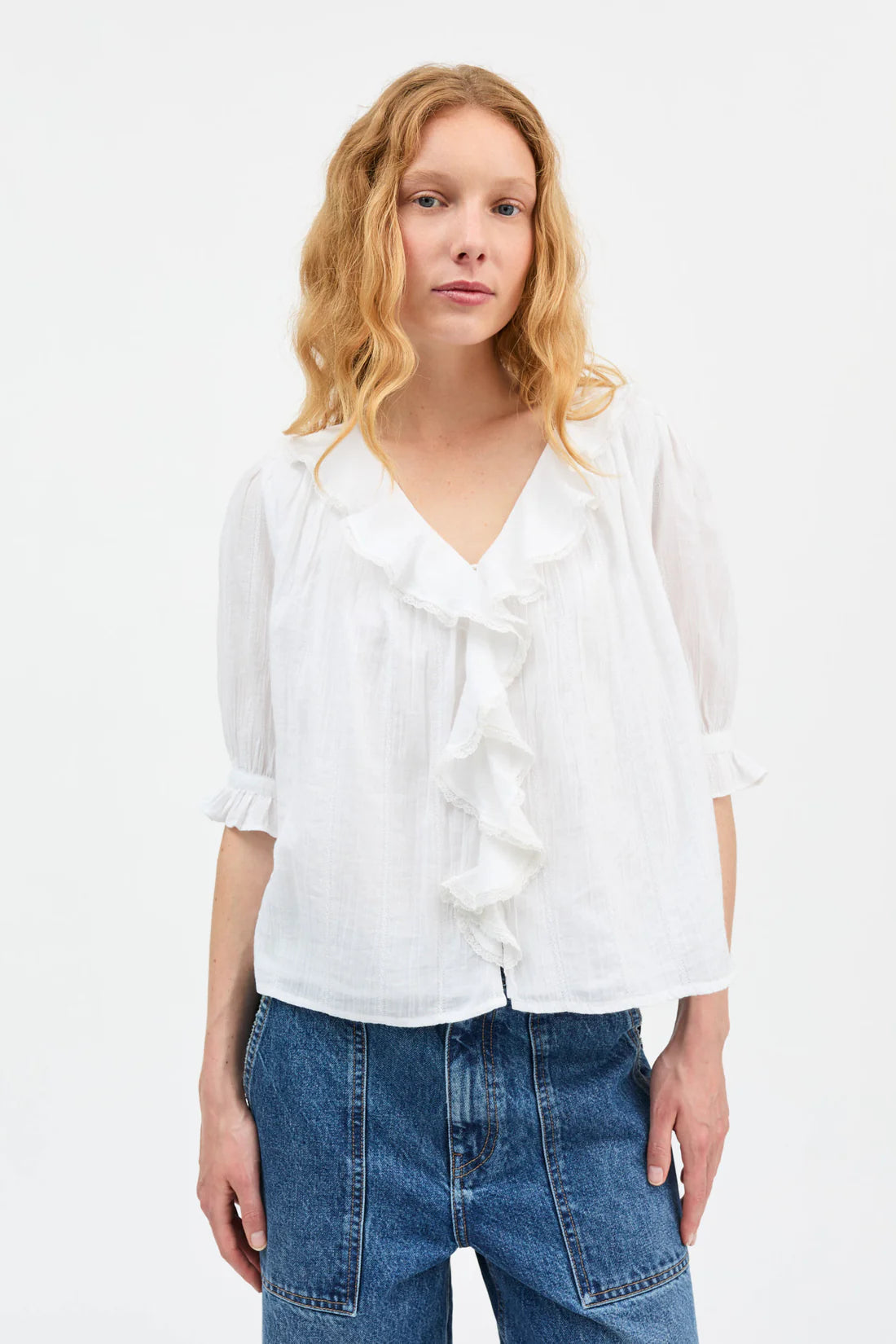 Woman wearing a white blouse and blue jeans on a white background