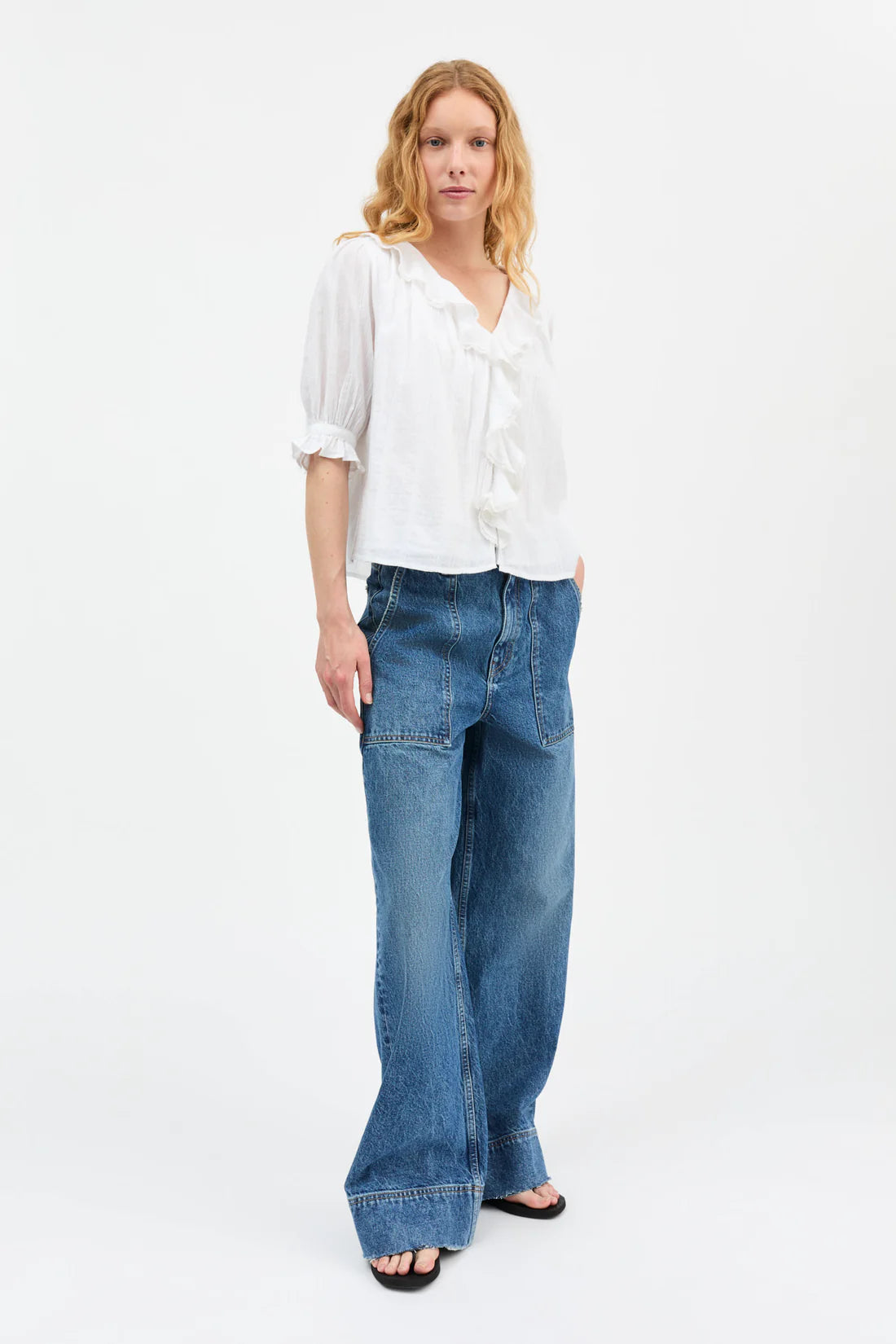 Woman wearing a white blouse and blue jeans on a white background