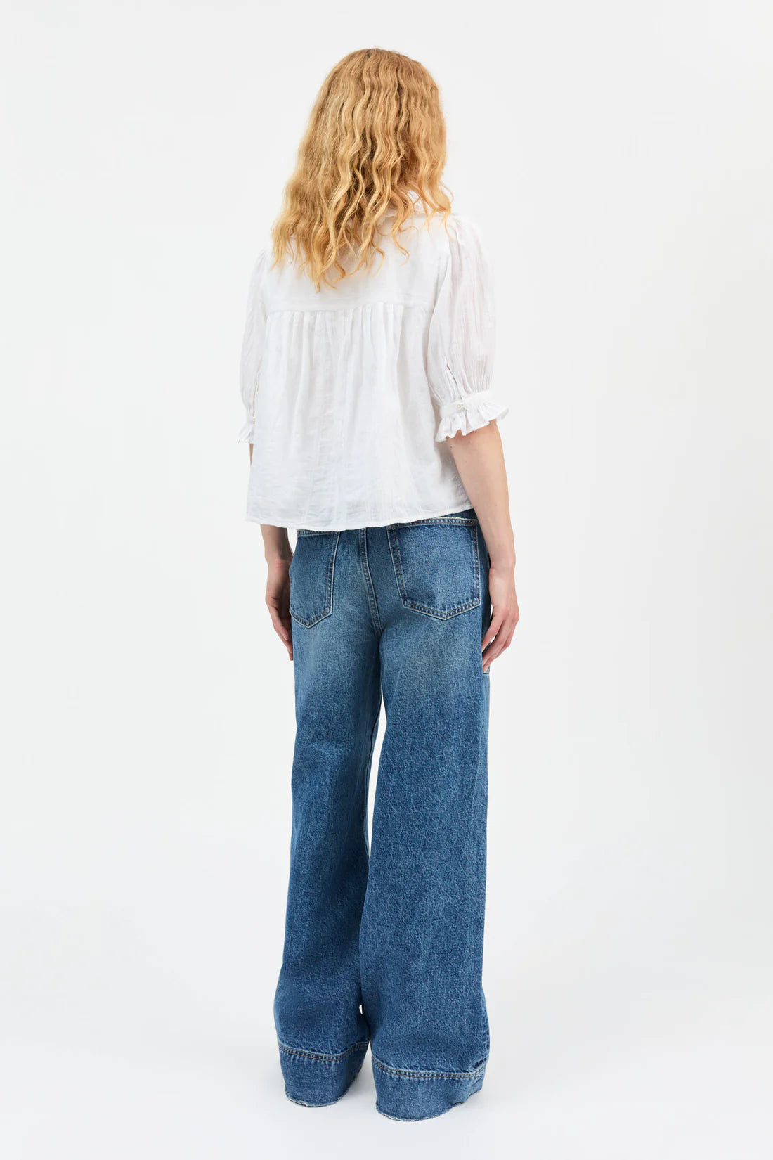 Person wearing a white blouse and blue jeans on a white background