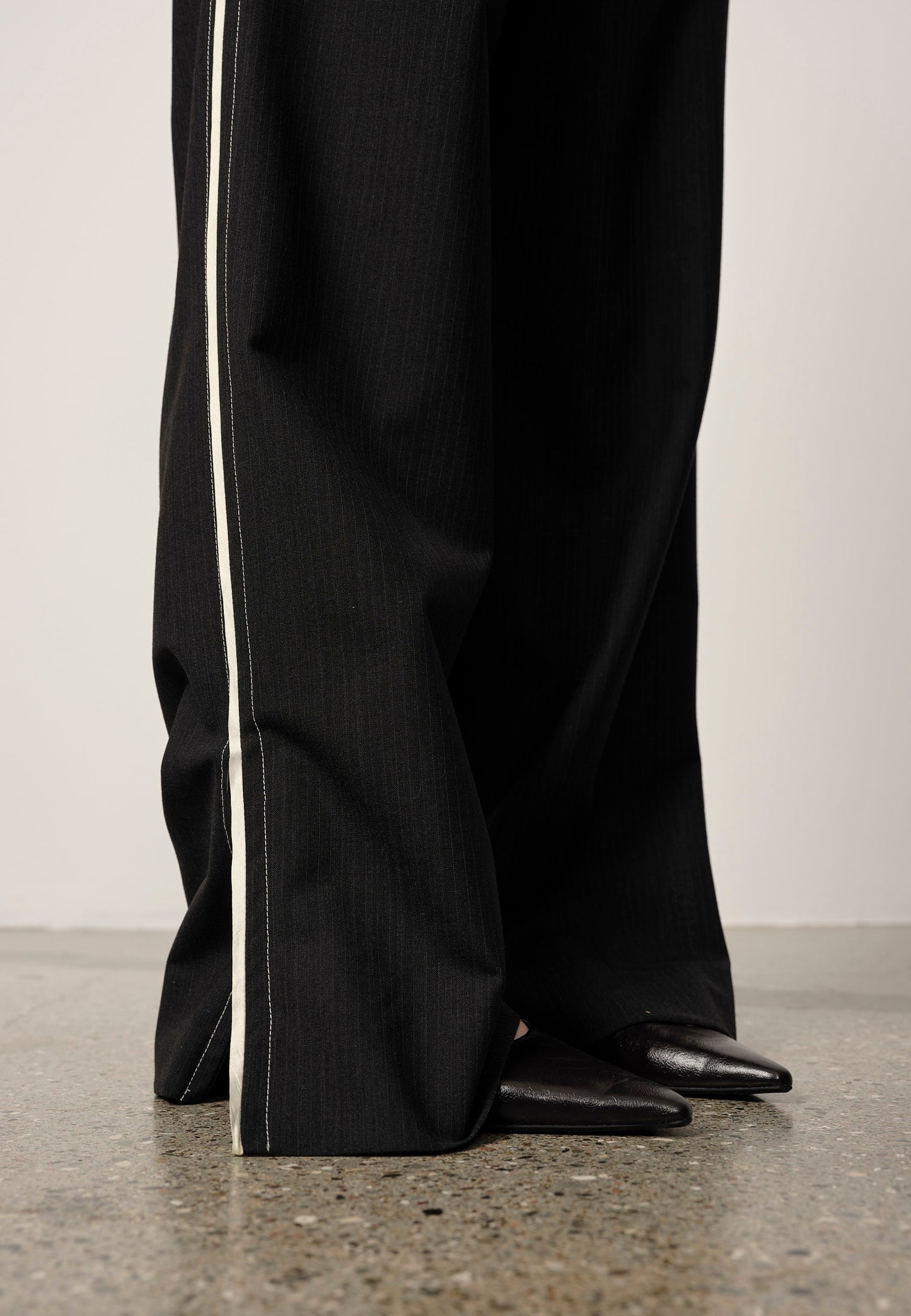 Black pants with a white stripe on a neutral background
