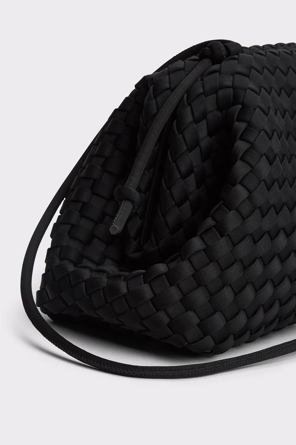 A close-up of a black woven leather shoulder bag with a matching black strap, set against a light gray background.