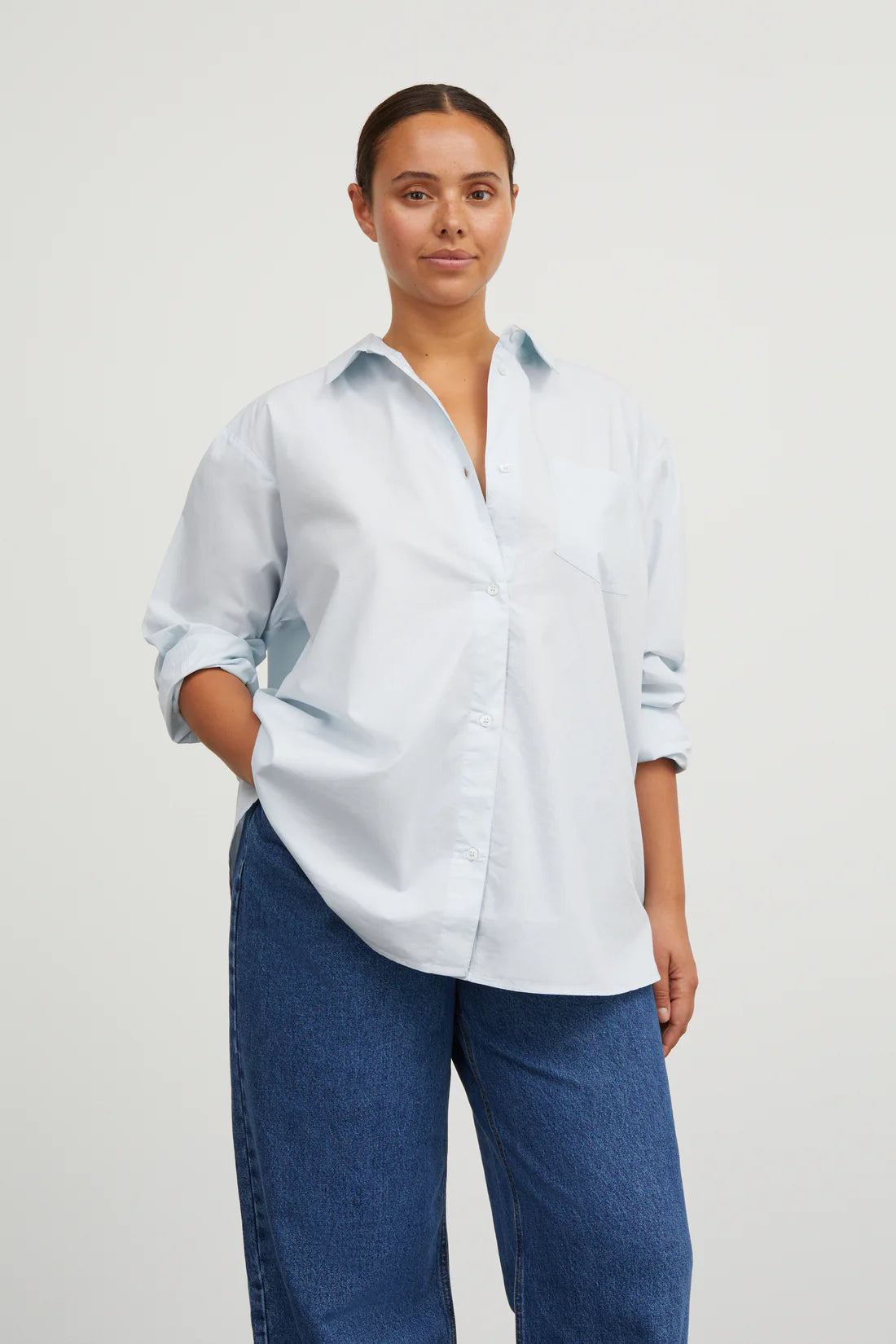 Woman wearing a light blue shirt and blue jeans on a white background