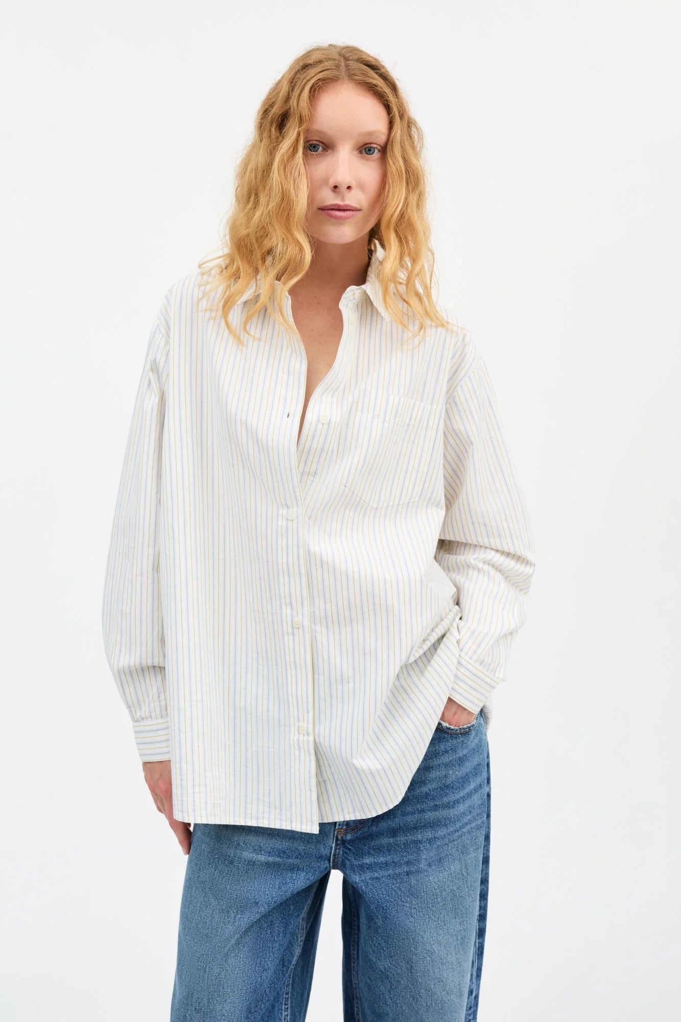 Woman wearing a white striped shirt and blue jeans on a white background