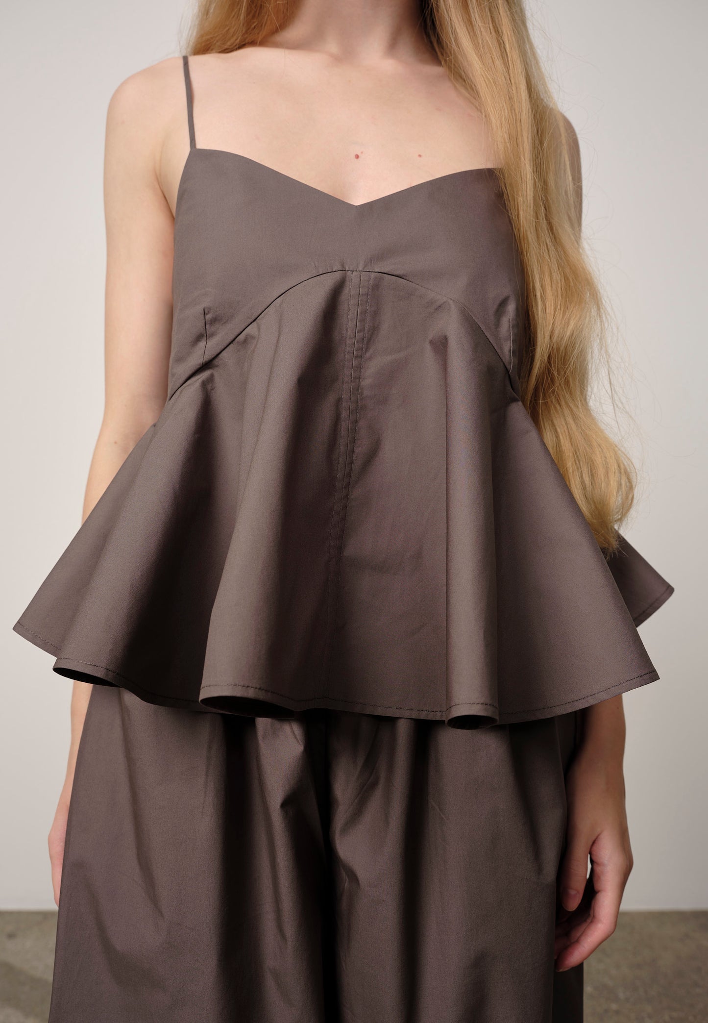 Brown peplum top worn by a person against a plain background
