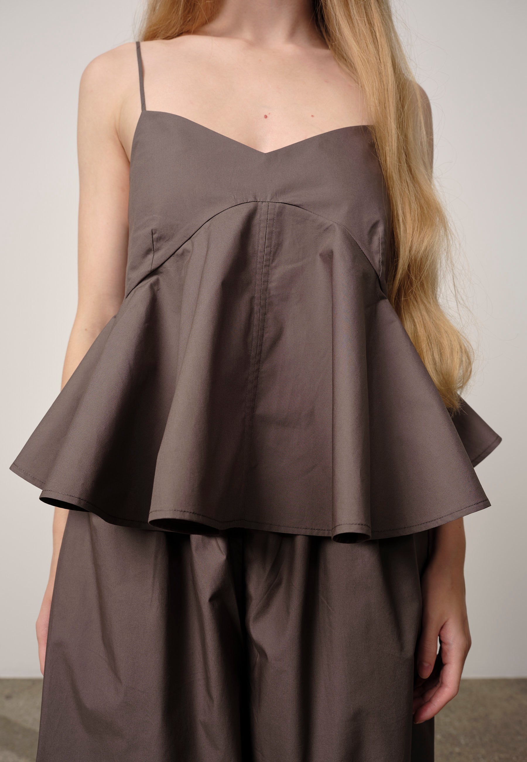 Brown peplum top worn by a person against a plain background