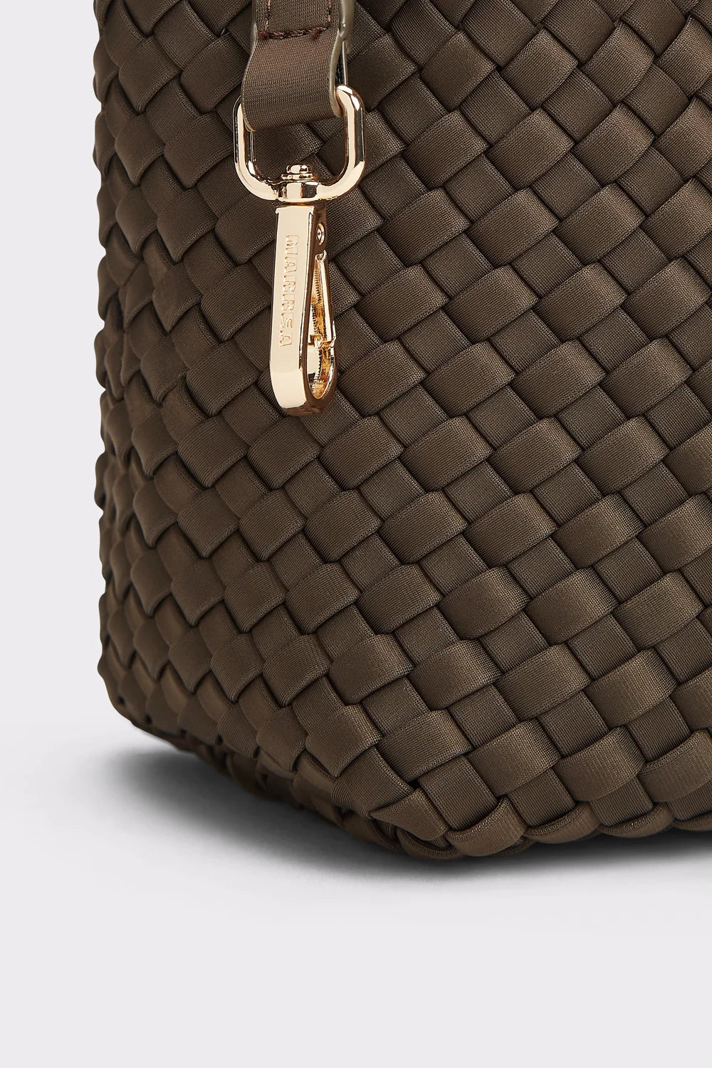 Close-up of a woven leather handbag in dark brown with a gold-tone metal clasp and a small vertical brand plaque.