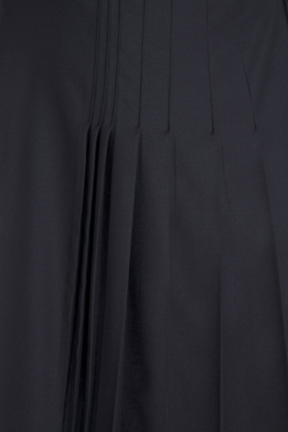 Close-up of a dark pleated fabric surface with vertical pleats and a smooth matte texture.