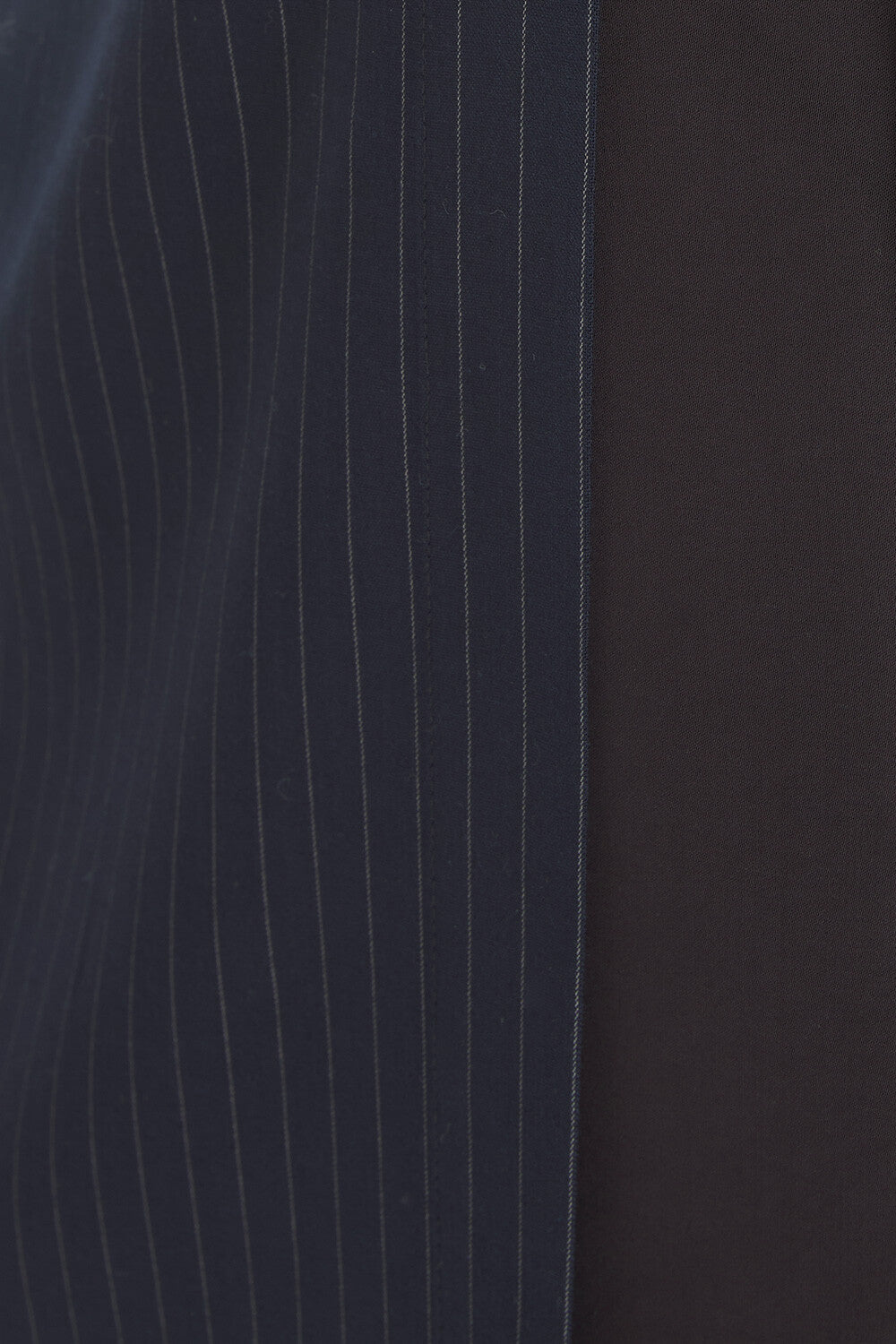Close-up of a dark navy blue pinstripe fabric next to a solid black fabric.