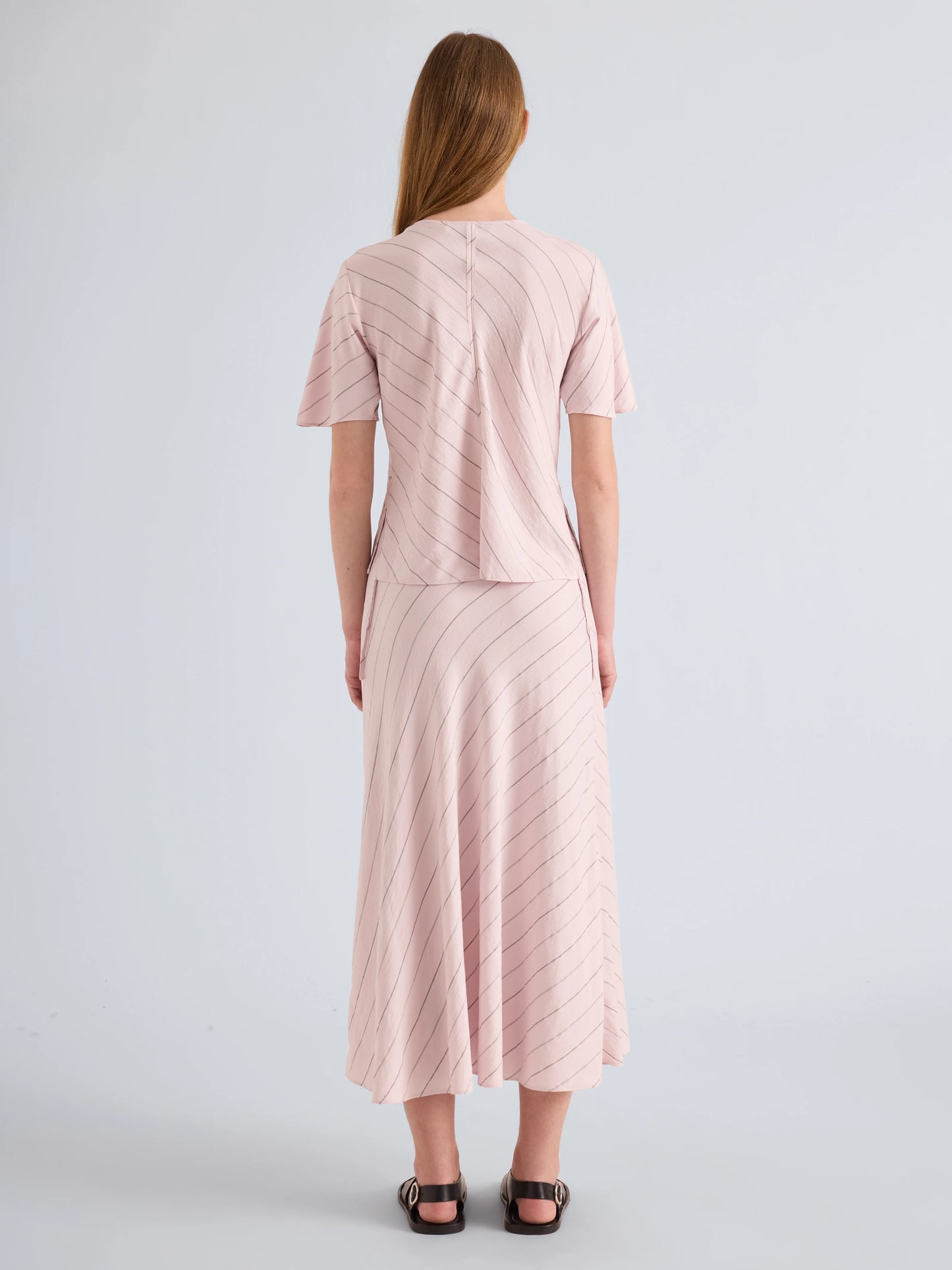 Woman wearing a pink textured dress against a light gray background