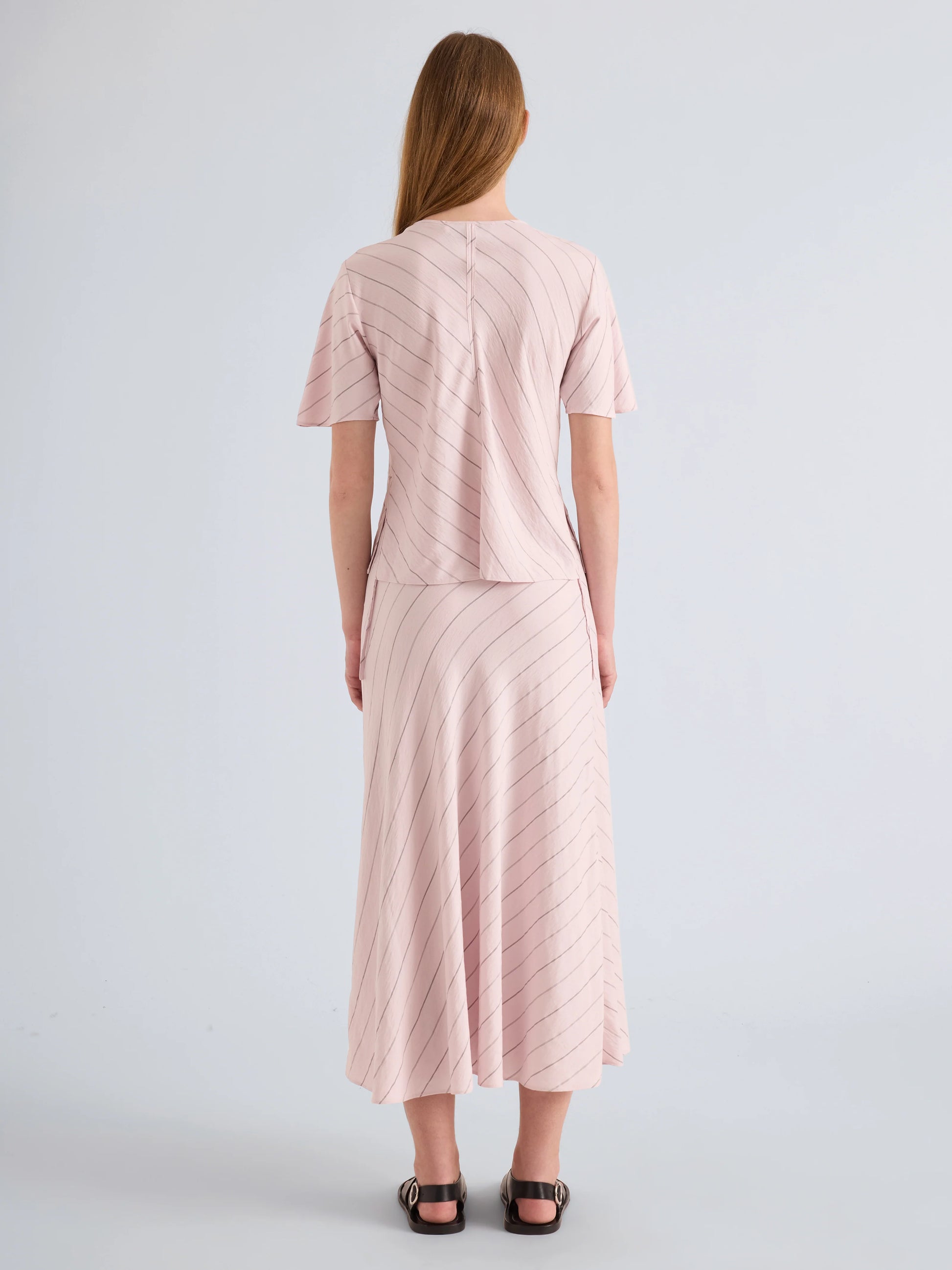 Woman wearing a pink textured dress against a light gray background