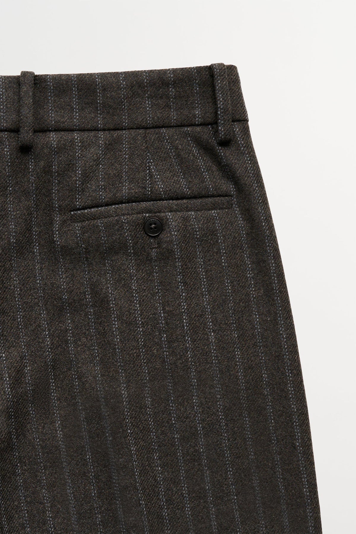 Close-up of dark brown pinstriped trousers showing the waistband, belt loops, and a rear welt pocket with a button closure.