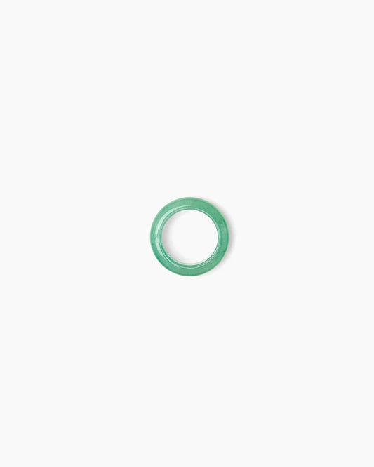 A pear-cut clear gemstone in a gold three-prong setting, centered on a solid white background with a soft reflection below.
