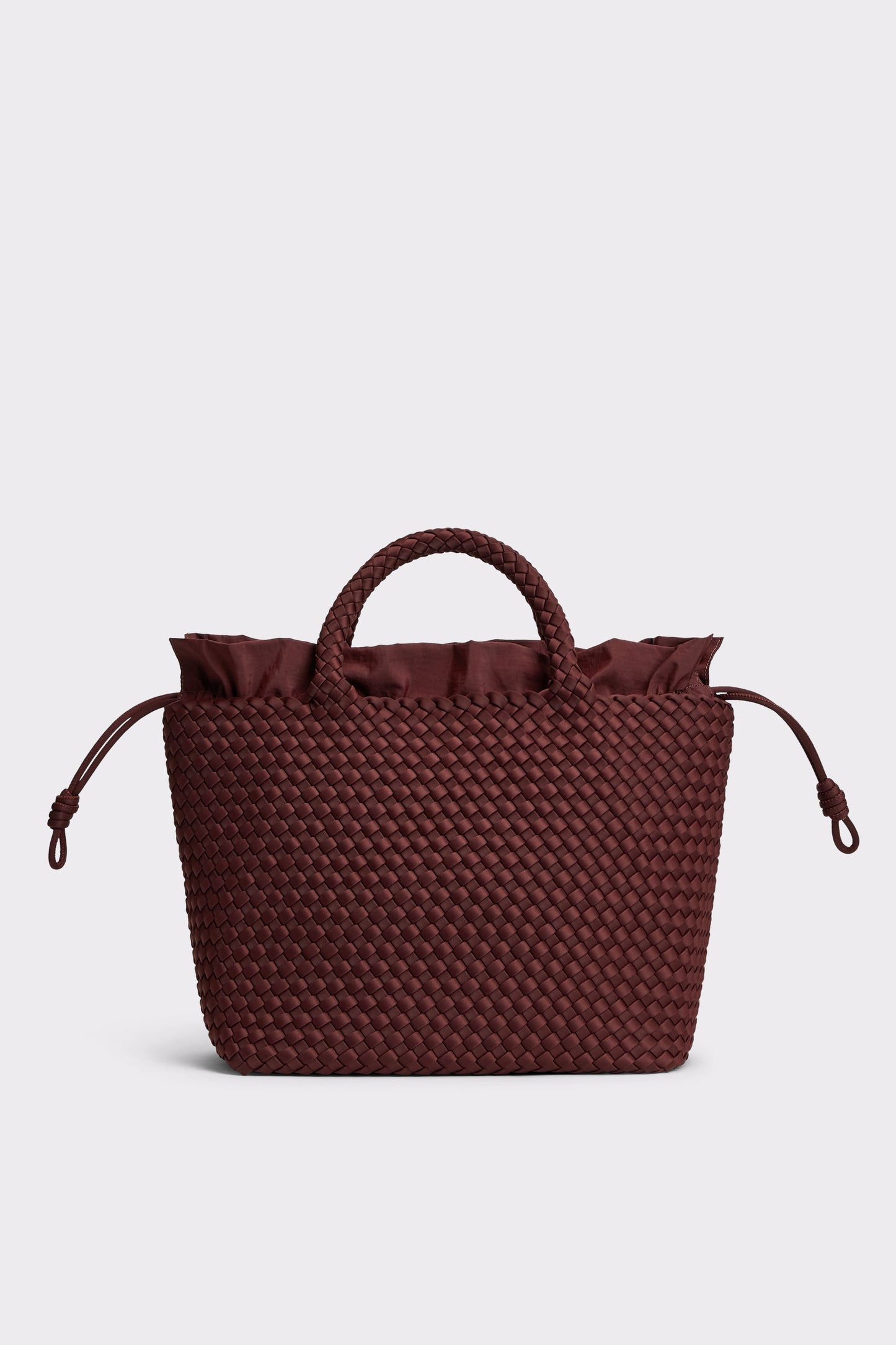 A dark burgundy woven tote bag with a top handle, ruffled trim at the top, and drawstring side details, shown against a light gray background.