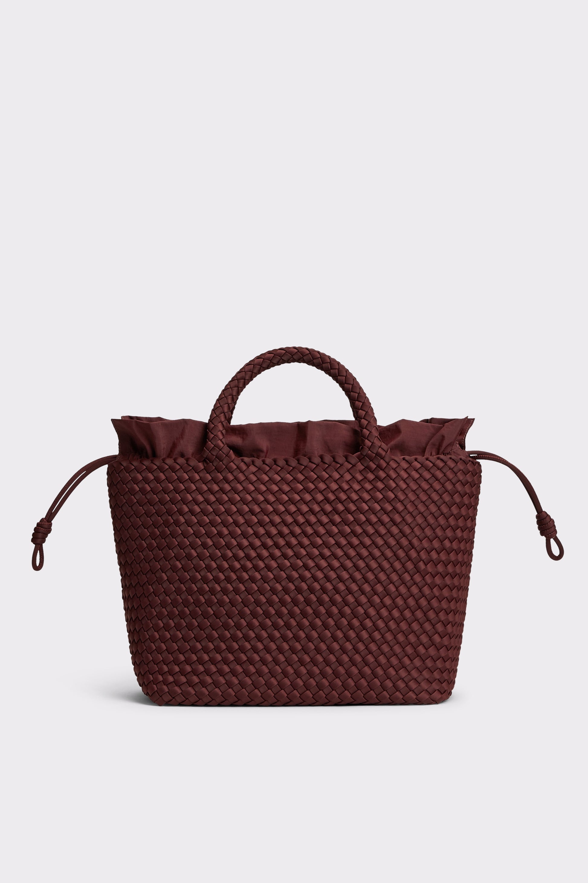 A dark burgundy woven tote bag with a top handle, ruffled trim at the top, and drawstring side details, shown against a light gray background.