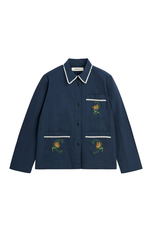 A navy blue button-up jacket with white trim on the collar and pocket edges, featuring embroidered yellow flowers with green stems on the chest and lower front pockets.