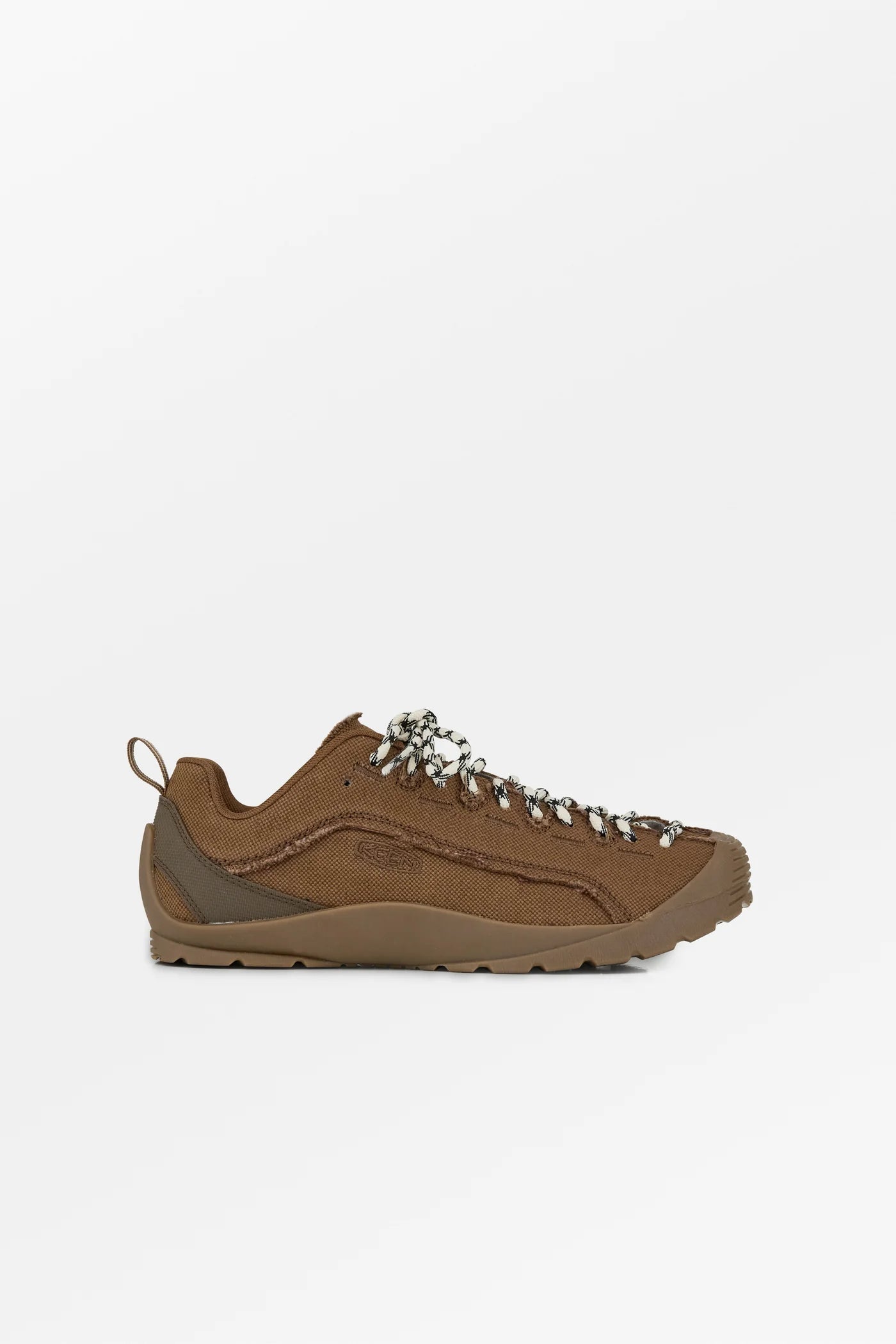 A brown suede sneaker with decorative silver metal eyelets and a thick brown sole, shown in profile against a light gray background.