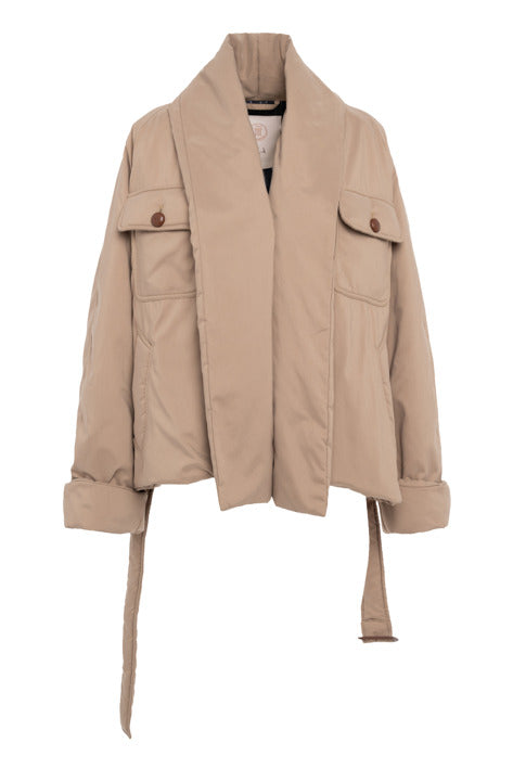 A beige utility-style jacket with a high collar, flap chest pockets with button closures, and a matching waist tie, shown against a plain white background.