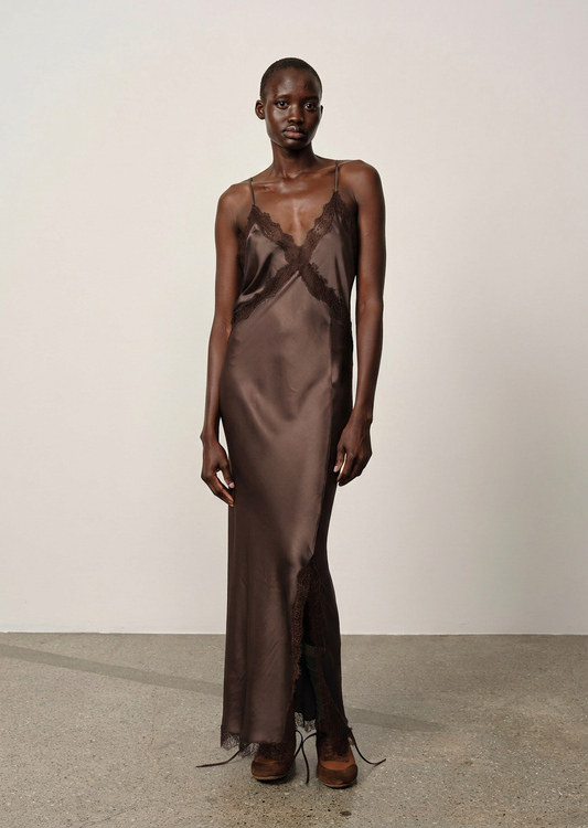 Model wearing a brown satin slip dress with lace details on a plain background