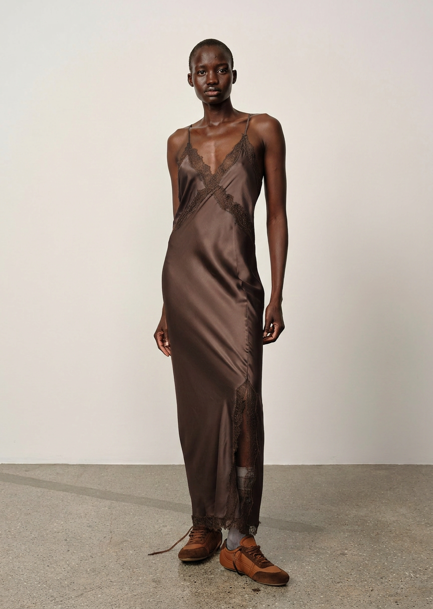 Model wearing a brown satin dress with sheer panels on a plain background
