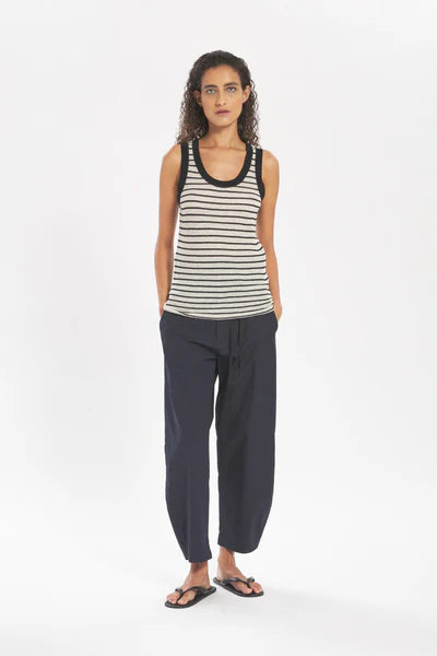 Woman wearing a striped tank top and dark pants on a white background