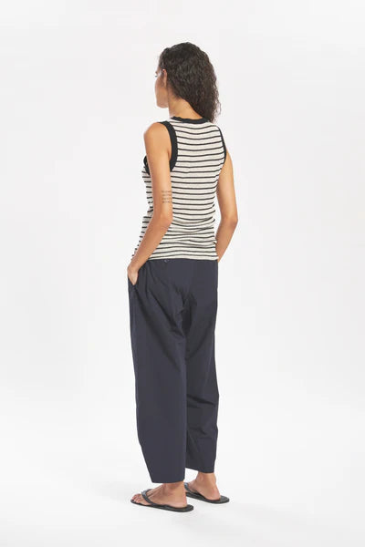 Person wearing a striped tank top and dark pants on a white background