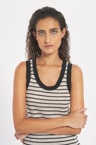 Woman wearing a black and white striped tank top against a plain background