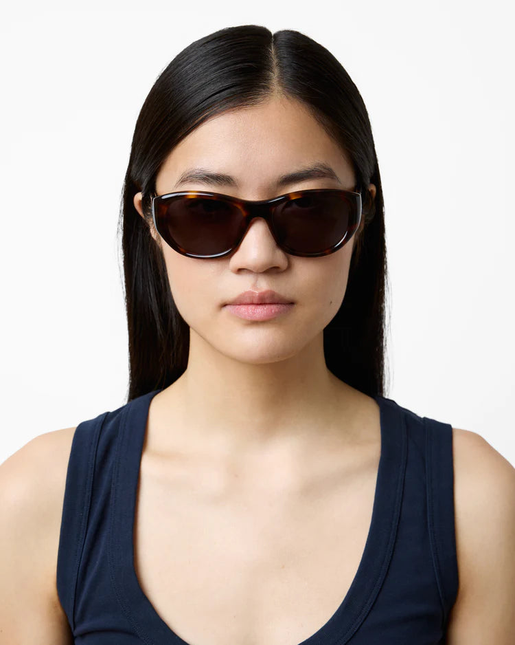Woman wearing dark sunglasses against a white background