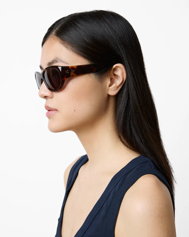 Woman wearing tortoiseshell sunglasses on a white background