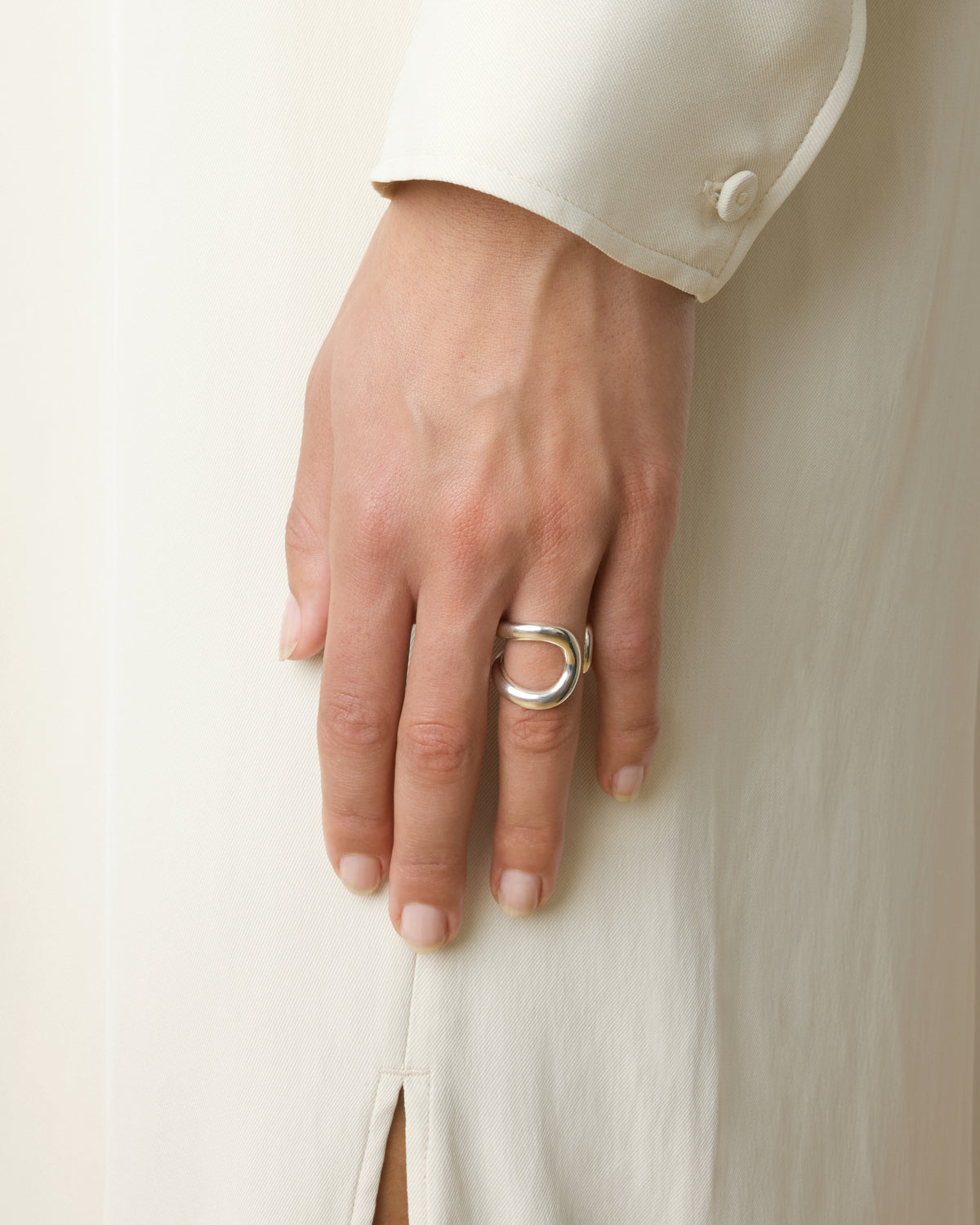 Hand wearing a silver ring on a plain background