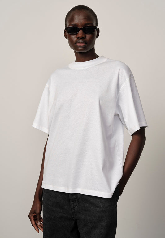 Person wearing a plain white t-shirt and dark sunglasses on a neutral background