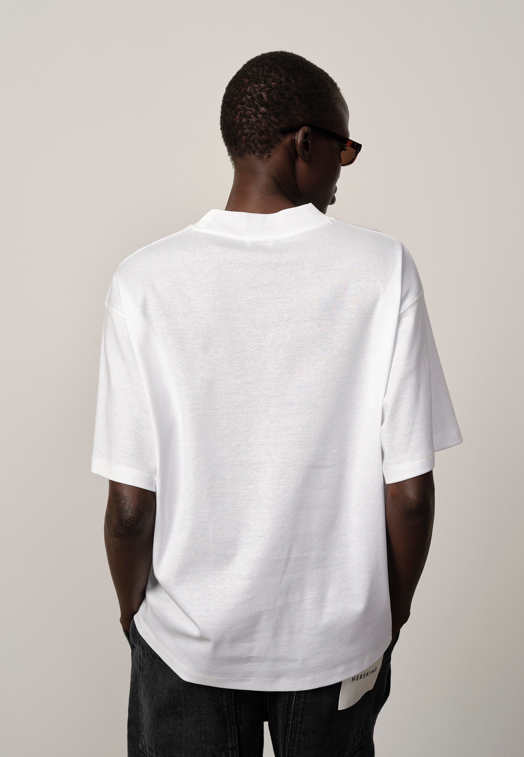 Person wearing a plain white t-shirt with a neutral background