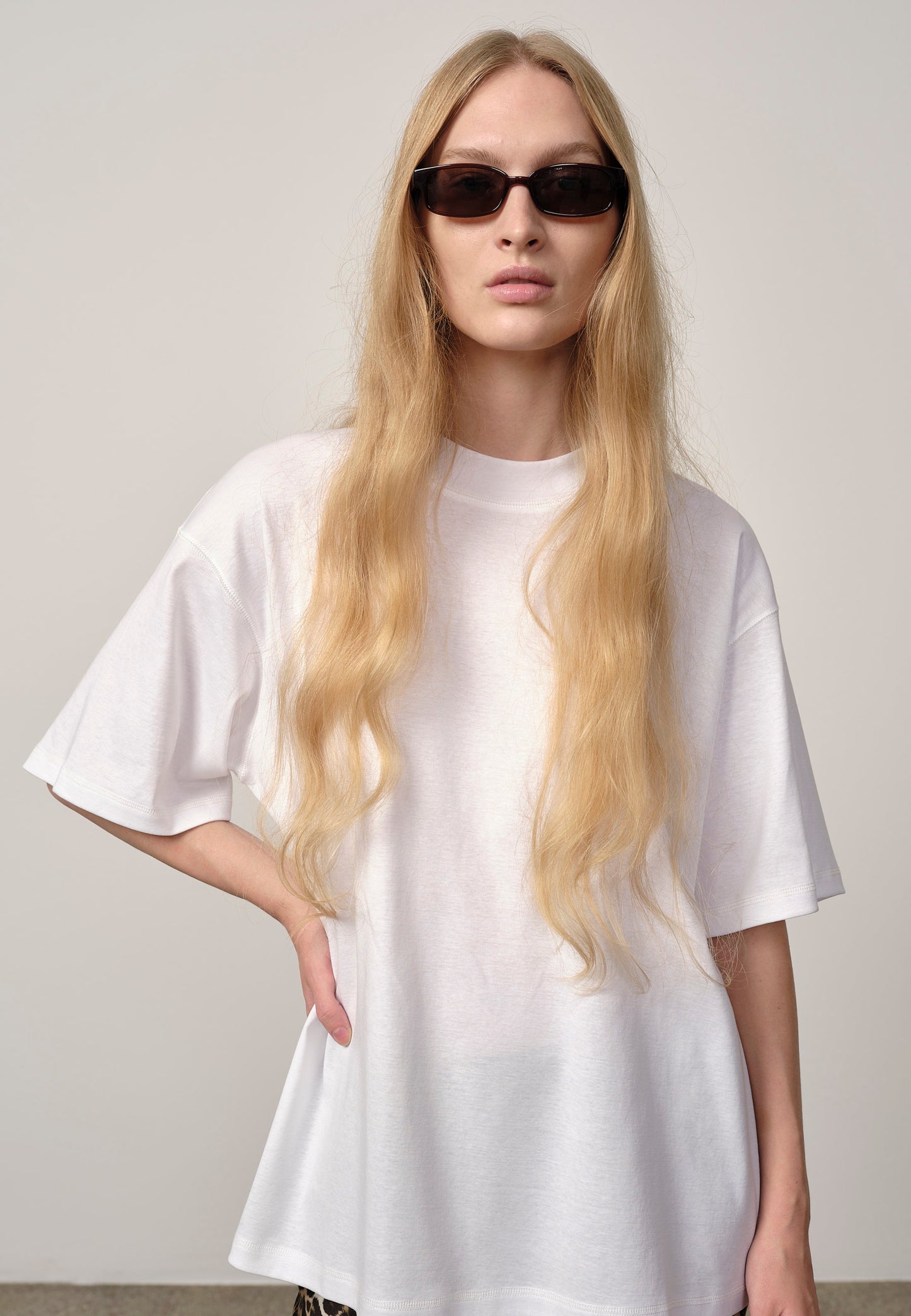 Person wearing a white t-shirt and sunglasses against a plain background