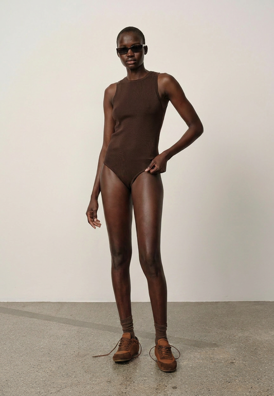 Person wearing a brown bodysuit and shoes on a plain background
