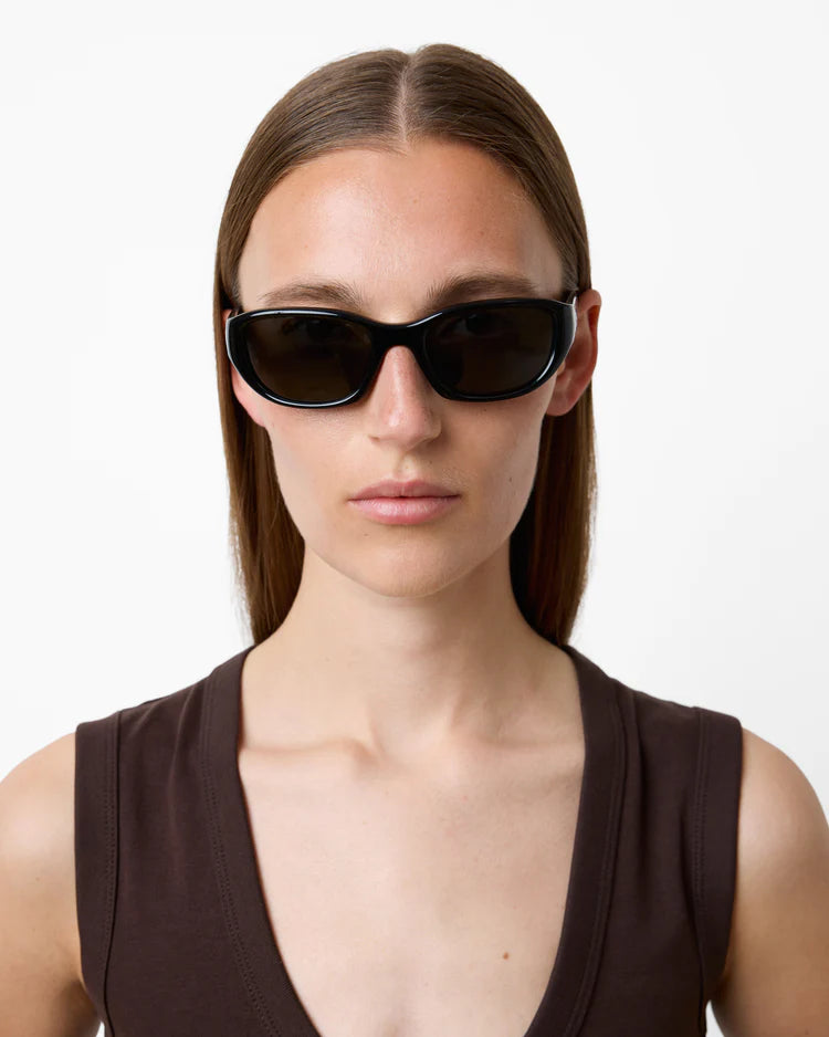 Woman wearing dark sunglasses against a white background