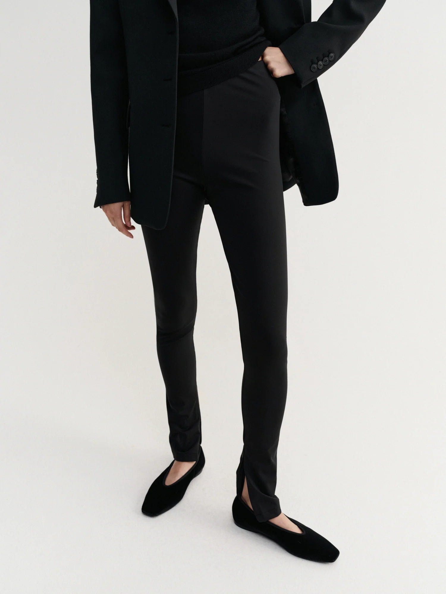 Person wearing a black suit and black shoes on a white background