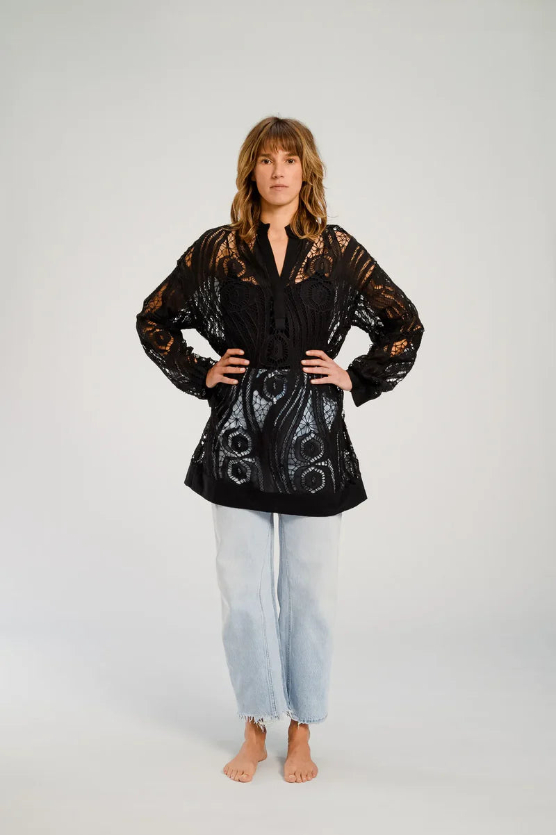 Woman wearing a black lace top and light blue jeans on a white background