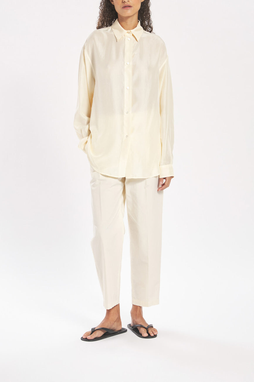 Person wearing a light-colored shirt and pants on a white background