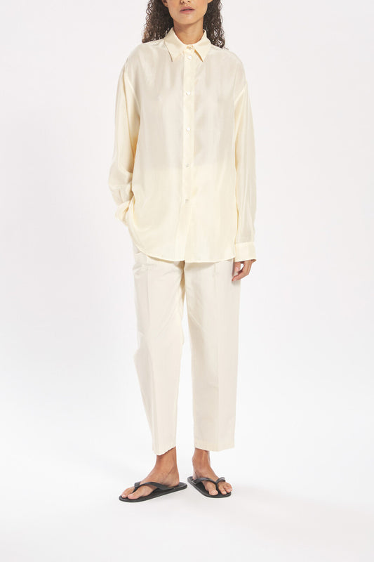Person wearing a light-colored shirt and pants on a white background