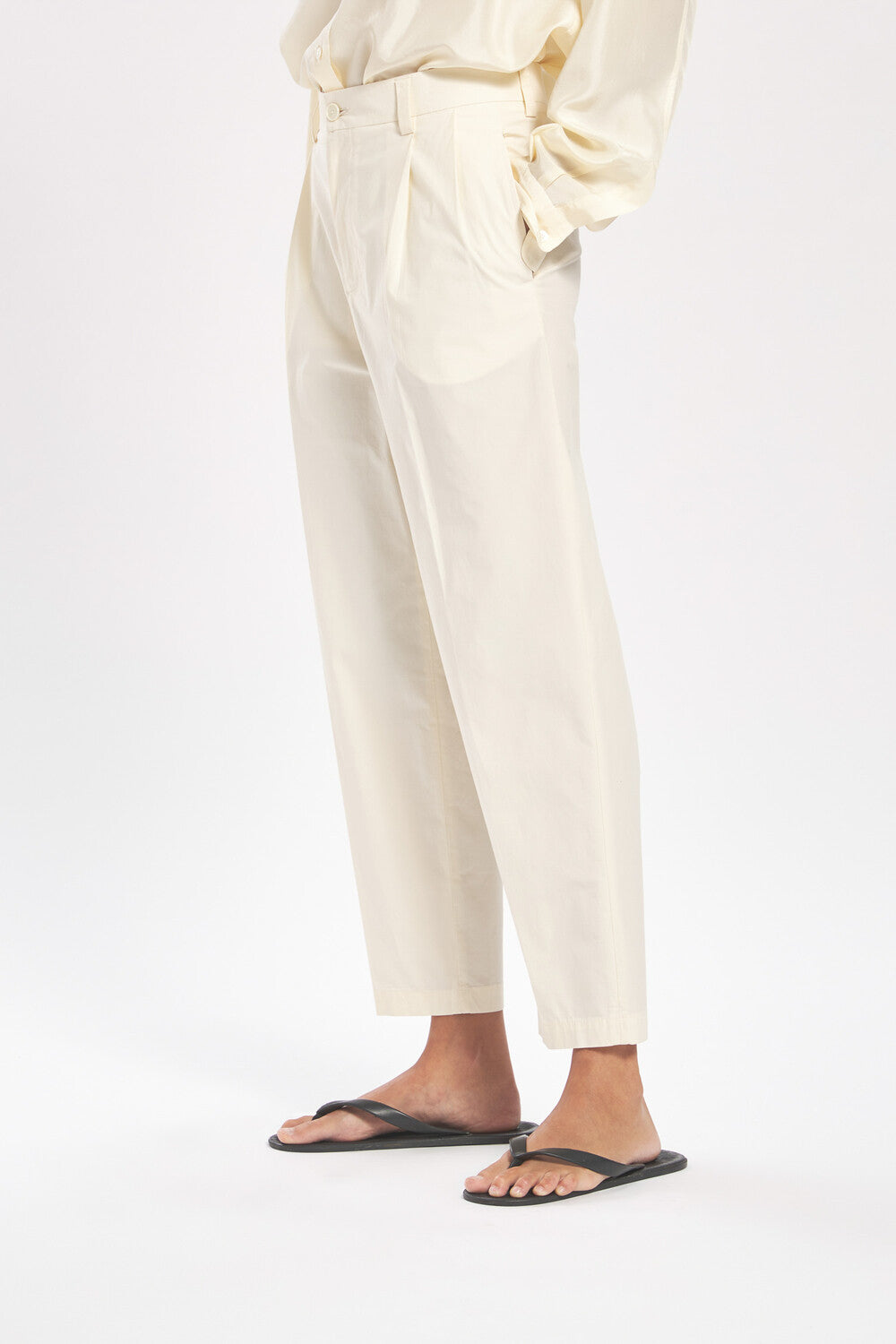 Person wearing light-colored pants and black sandals on a white background