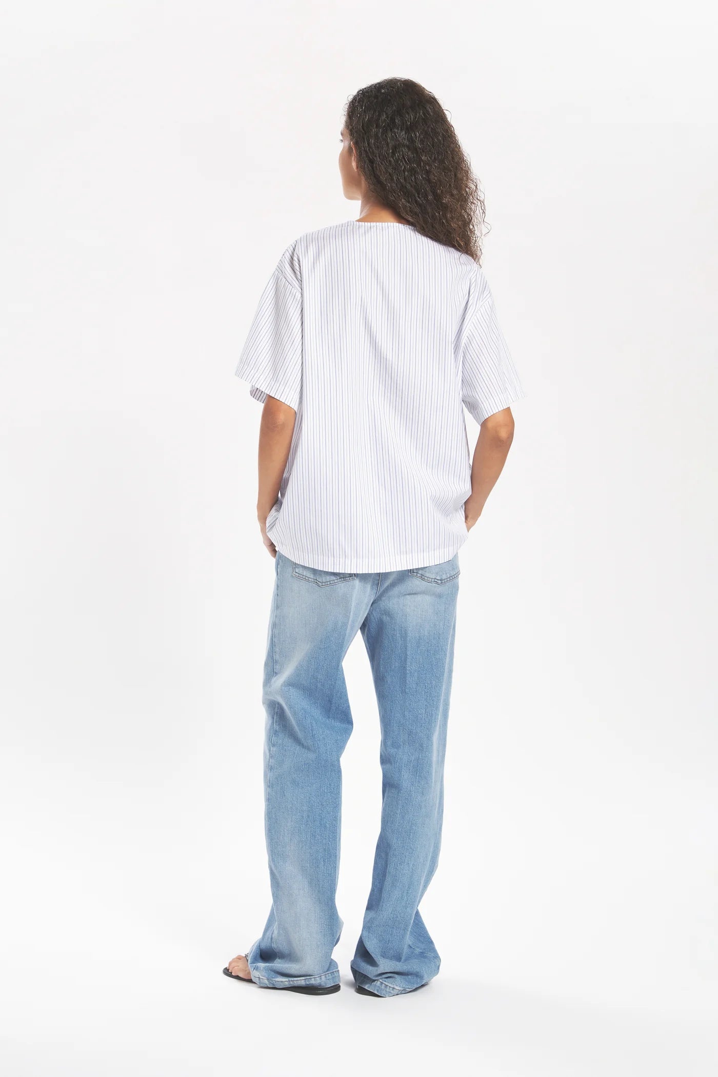Person wearing a white shirt and blue jeans on a white background