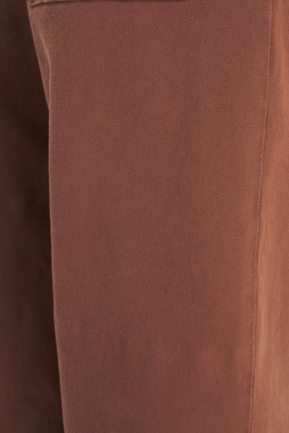 Close-up of a brown textured fabric surface with visible weave and a vertical seam.