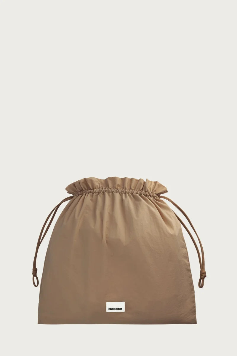 Brown drawstring bag with a brand label on a light beige background